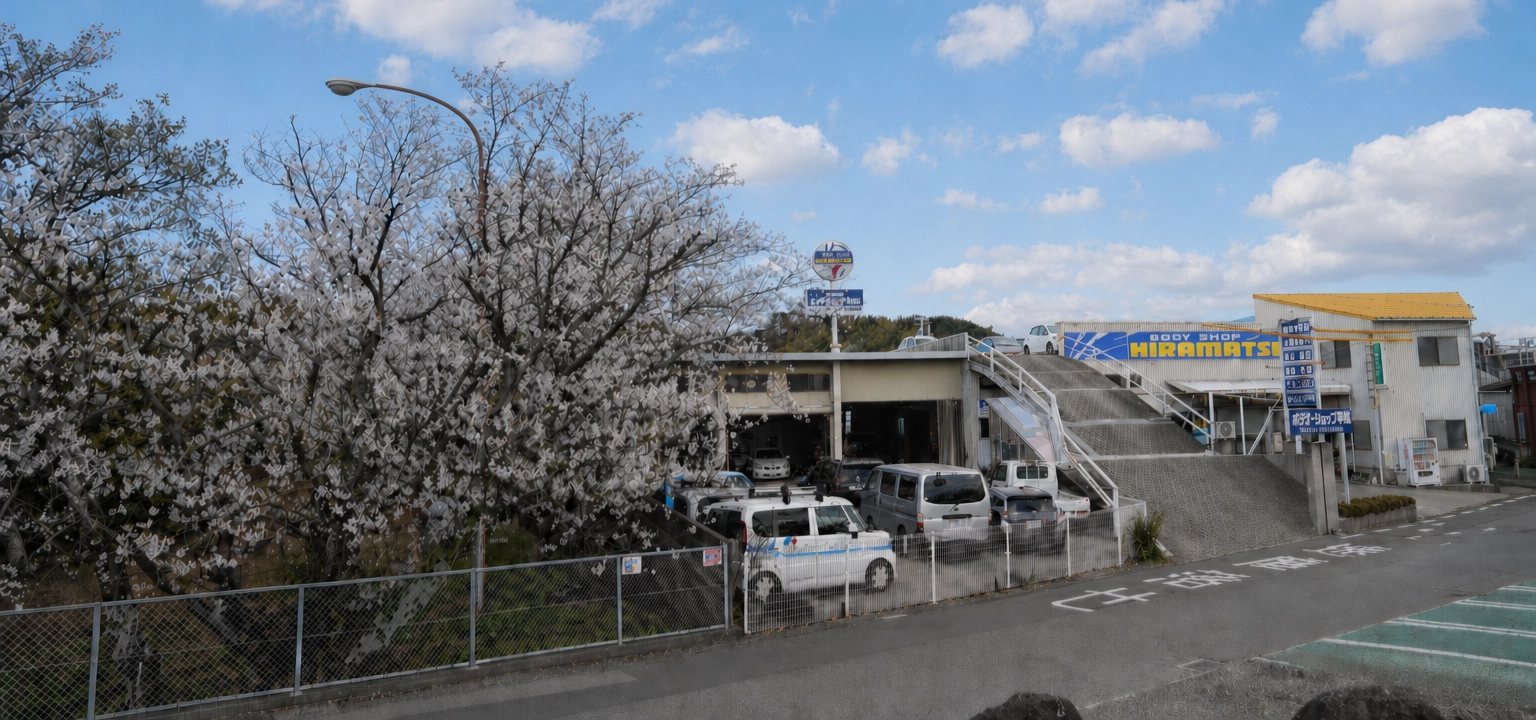 桜並木のそばにあるボデーショップ平松の社屋外観